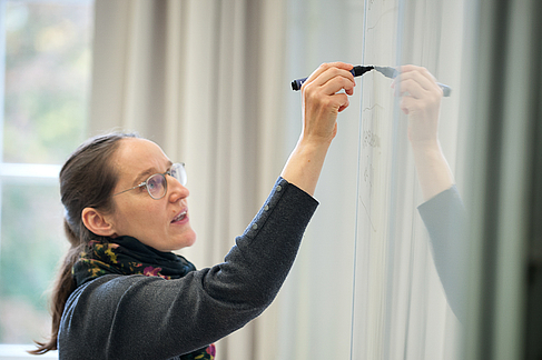 Professorin schreibt etwas an die Tafel
