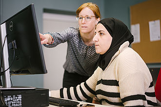 Professorin zeigt einer Studentin etwas am Bildschirm